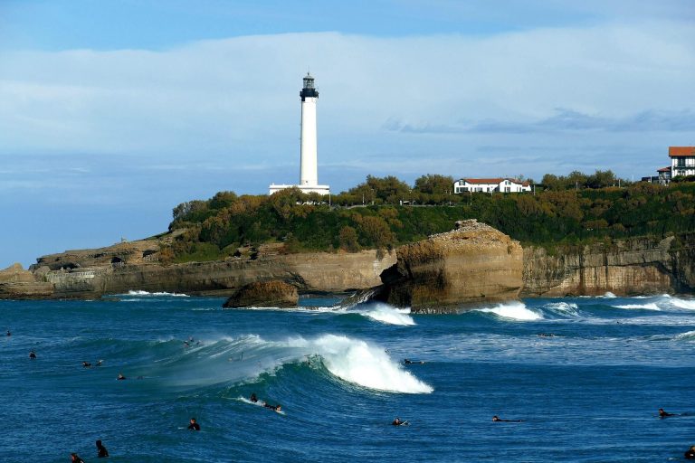 Le phare de Biarritz guidant des surfeurs, une métaphore de la vision stratégique et du leadership pour un séminaire d'entreprise.