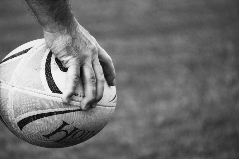 Main tenant un ballon de rugby, symbole des valeurs de solidarité et d'intelligence collective pour un team building à Biarritz.