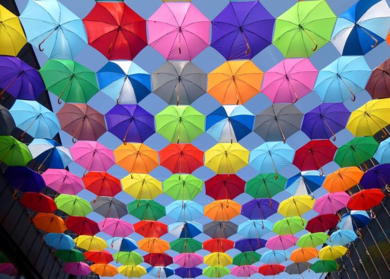 Une installation de parapluies colorés flottant au-dessus d'une rue, symbolisant nos solutions de team building disponibles partout en France.