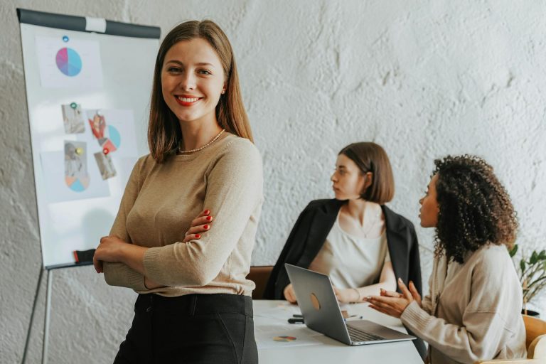 Portrait d'une femme leader, bras croisés et souriante, symbolisant l'intelligence émotionnelle réelle et l'ajustement de posture en direct.