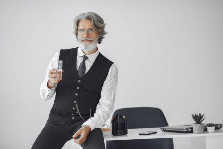 Un dirigeant assis sur le bord de son bureau tient un verre d'eau, illustrant une posture de management fondée sur la délégation, la confiance et l'autonomie des équipes.